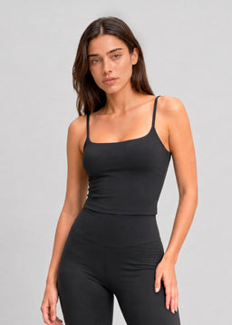 Femme portant un débardeur de sport noir à brassière intégrée et fines bretelles Onalie avec un legging assorti