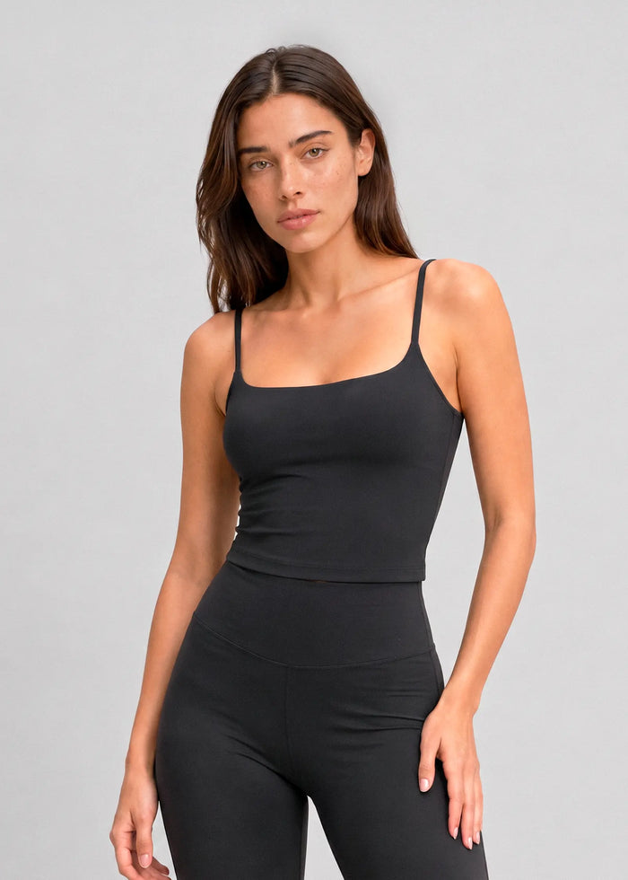 Femme portant un débardeur de sport noir à brassière intégrée et fines bretelles Onalie avec un legging assorti