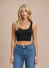 Femme portant le crop top sculptant noir à brassière intégrée Onalie avec un jean bleu, vue de face