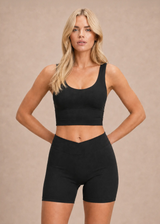 Femme portant le crop top de sport noir à brassière intégrée Onalie avec un short taille haute, vue de face