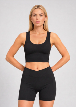 Femme portant un crop top de sport noir à brassière intégrée avec larges bretelles et un short cycliste noir assorti.