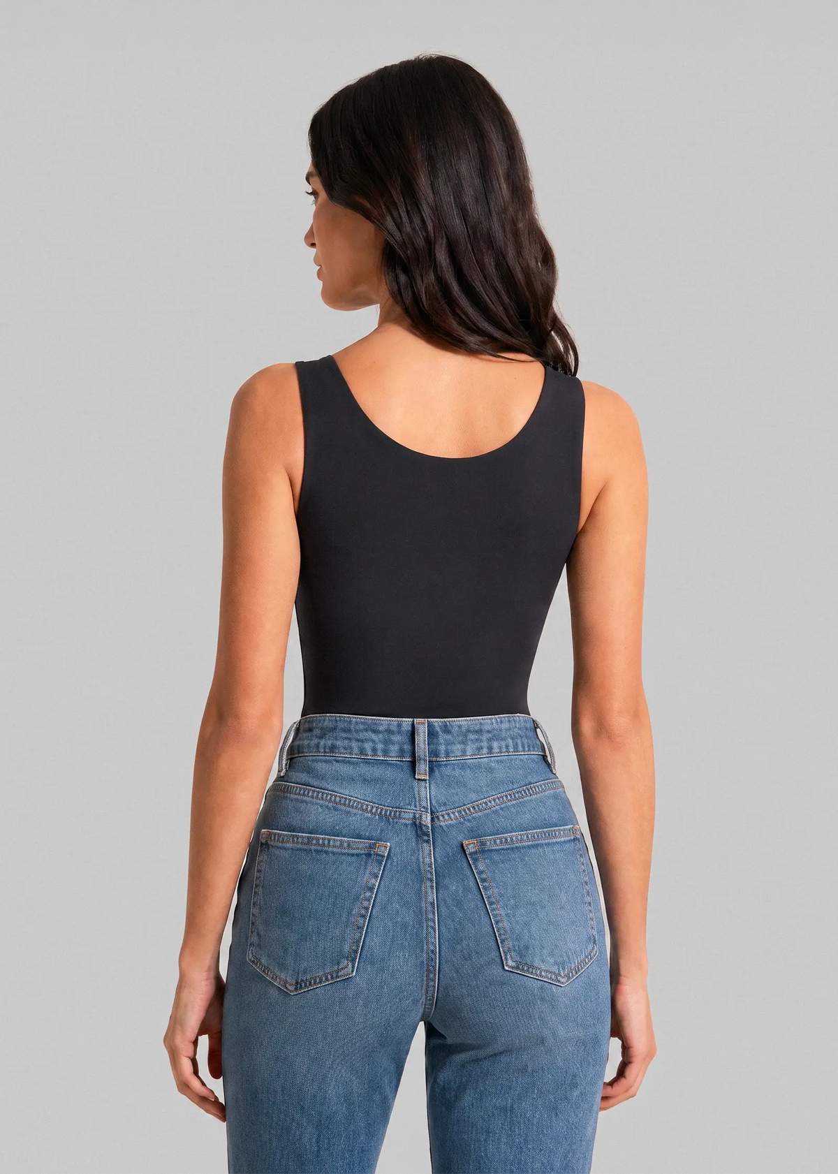 Femme portant un débardeur sculptant noir à soutien-gorge intégré sans armatures Onalie, vue de dos avec un jean bleu