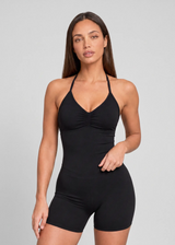 Femme portant un top noir à brassière intégrée avec col halter et fronces sur le devant.