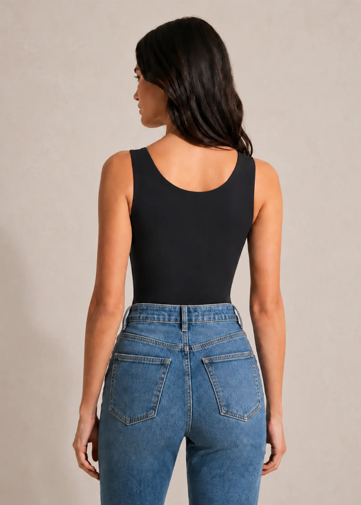 Femme portant le top sculptant noir à brassière intégrée Onalie, vue de dos avec un jean bleu