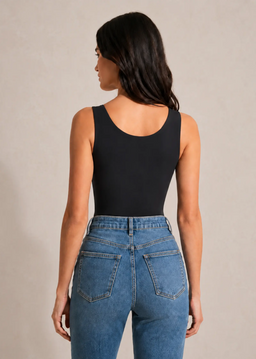 Femme portant le top sculptant noir à brassière intégrée Onalie, vue de dos avec un jean bleu